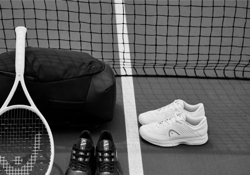Schläger, Tasche und Schuhe vor einem Tennisnetz